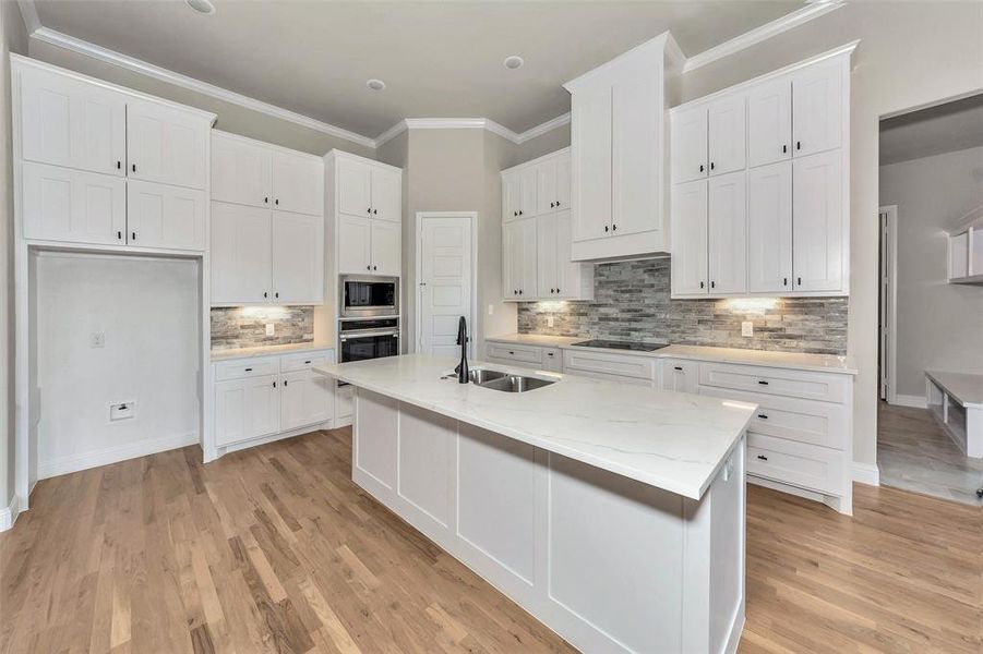 Kitchen featuring sink, light hardwood / wood-style flooring, decorative backsplash, and appliances with stainless steel finishes