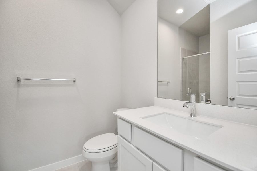 Secondary bath features tile flooring, bath/shower combo with tile surround, light stained wood cabinets, beautiful light countertop. Sample photo of completed home with similar floor plan. Actual colors and selections may vary.