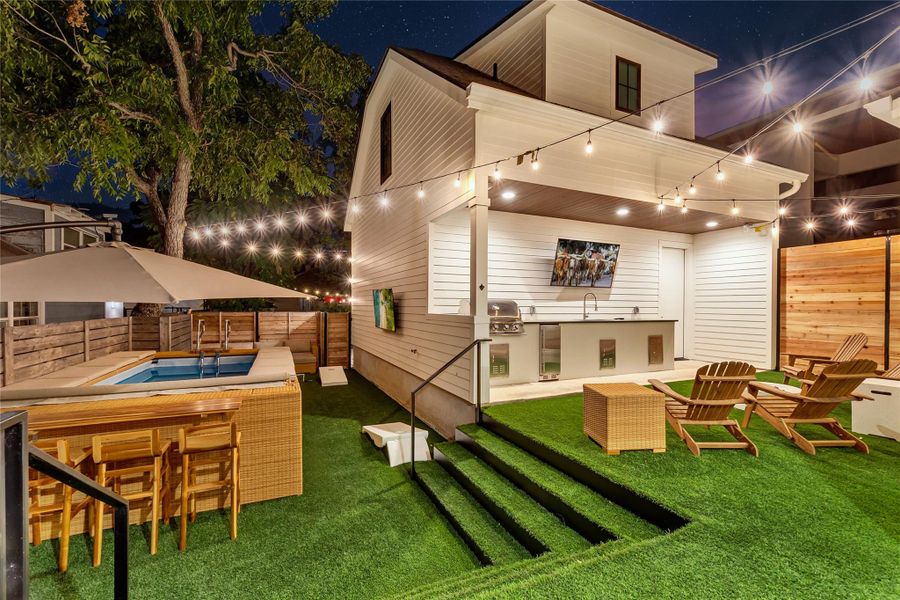 Back of house at night featuring a fenced backyard, area for grilling, a patio, and a swimming pool Back of house at night featuring a fenced backyard, area for grilling, a patio, and a swimming pool