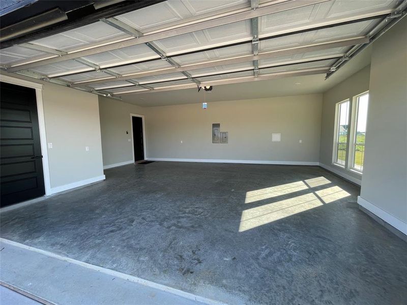Spacious two-car garage featuring a concrete floor, light gray painted walls, and white baseboards