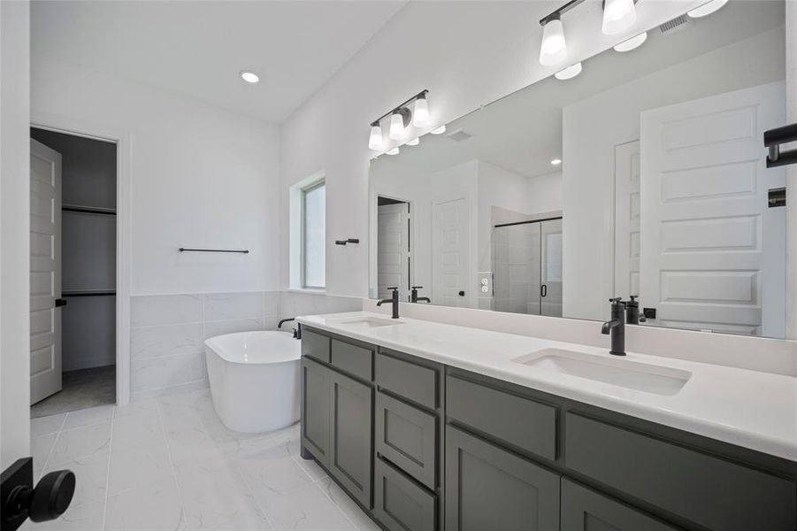 Bathroom with plus walk in shower, tile patterned flooring, vanity, and tile walls