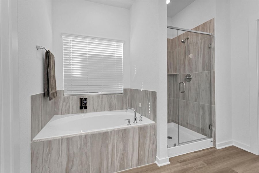 This serene primary bath retreat features a soaking tub, glass-enclosed walk-in shower, and elegant tile finishes, creating a spa-inspired space for relaxation.