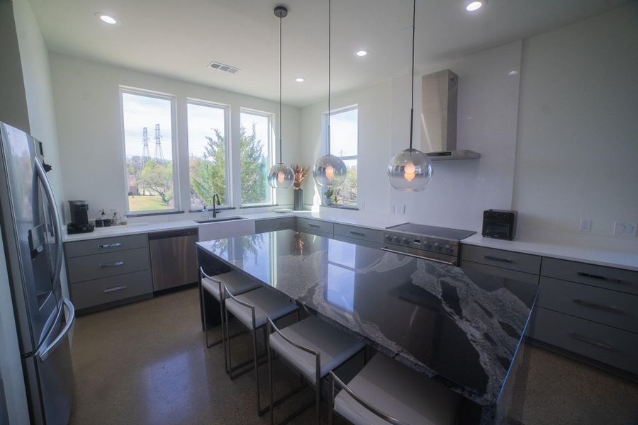 The sleek dark counter top offers space for bar stools, perfect for entertainment while a meal gets prepped in this modern kitchen.