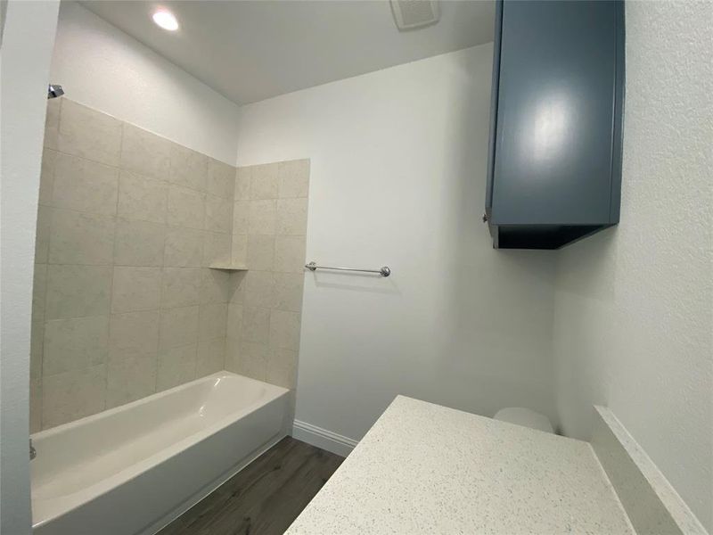 Bathroom featuring dark wood-style floors, bathtub / shower combination, and vanity Bathroom featuring dark wood-style floors, bathtub / shower combination, and vanity