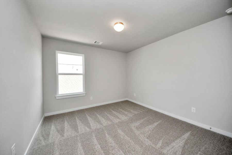 Secondary bedroom features plush carpeting, large windows that let in plenty of natural light, bright paint, and spacious closets. Sample photo of completed home with similar floor plan. Actual colors and selections may vary.