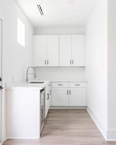 View of wet bar area by Game Room with storage and beverage fridge