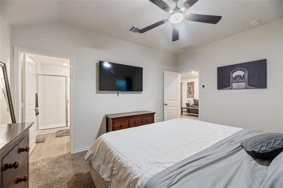 Bedroom featuring light carpet, a ceiling fan, and ensuite bathroom