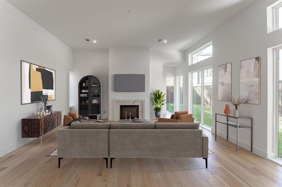 Living room with light hardwood / wood-style floors and a towering ceiling