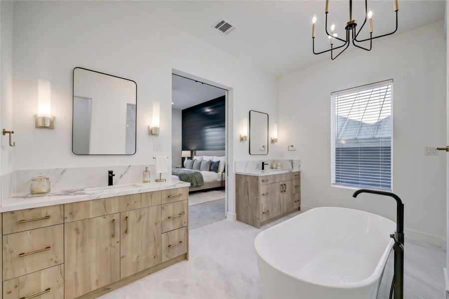 Primary Bath – Elegantly appointed with double vanities topped with quartz countertops, designer sconces and a statement lighting fixture.