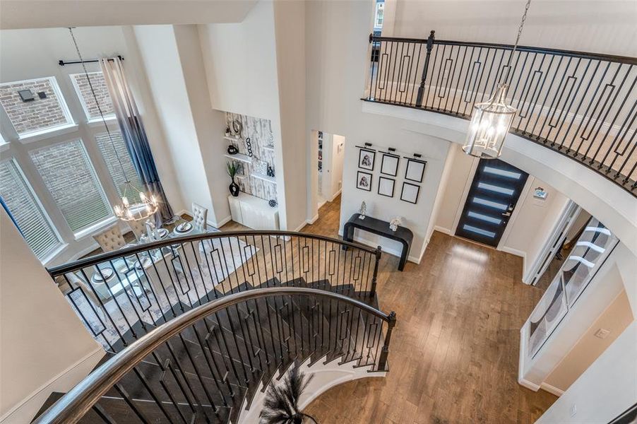 Staircase featuring a chandelier, a towering ceiling, wood finished floors, and arched walkways