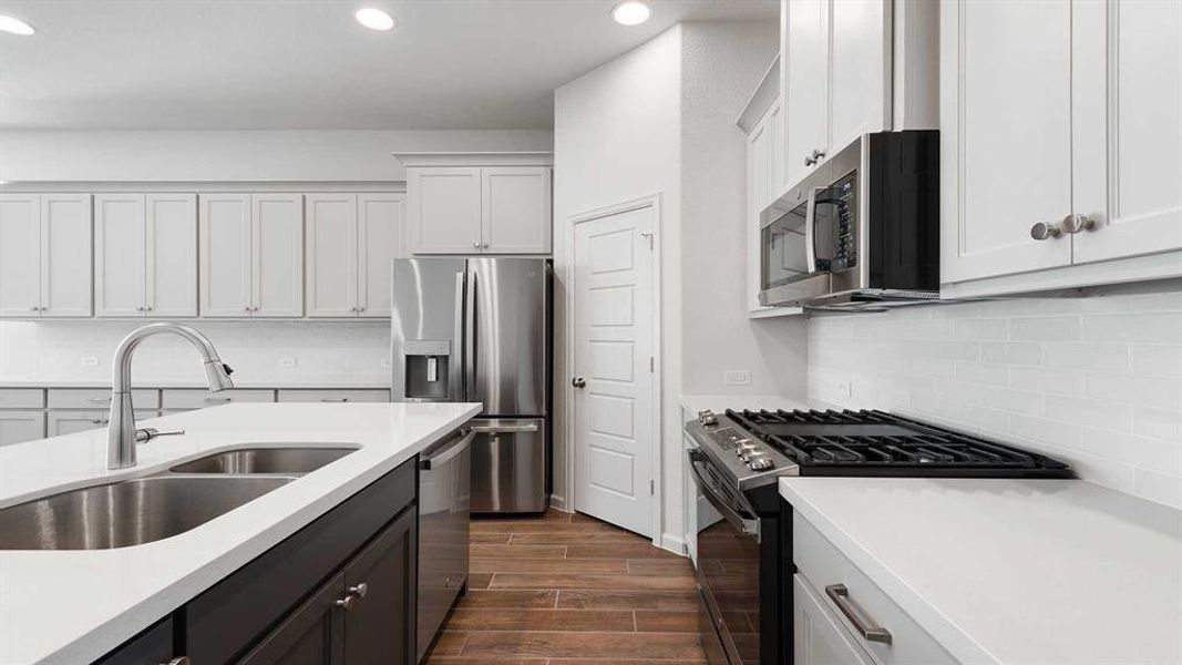 Kitchen featuring backsplash, sink, white cabinets, and stainless steel appliances