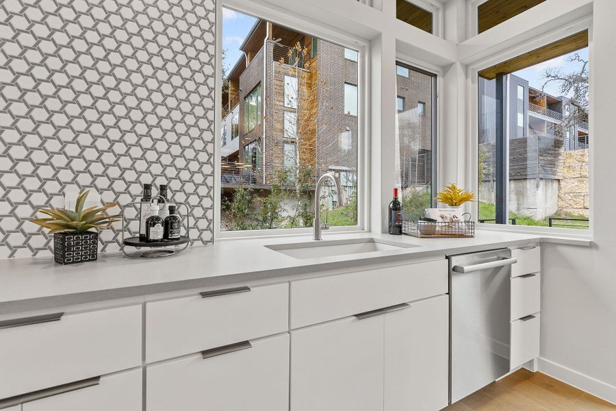 Kitchen featuring white cabinetry, light countertops, and a sink