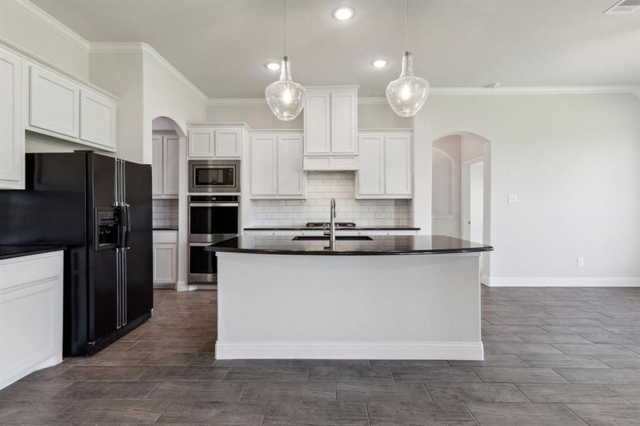 The well lit Kitchen highlights pendant lighting, ornamental molding, stainless steel double ovens & microwave.  Not to miss is the Butler's pantry & bright white picture frame cabinets...