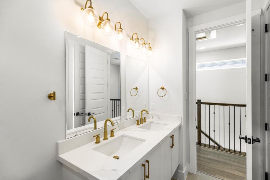 Elegant bathroom with dual sinks, quartz counters, and gold fixtures. Elegant bathroom with dual sinks, quartz counters, and gold fixtures.