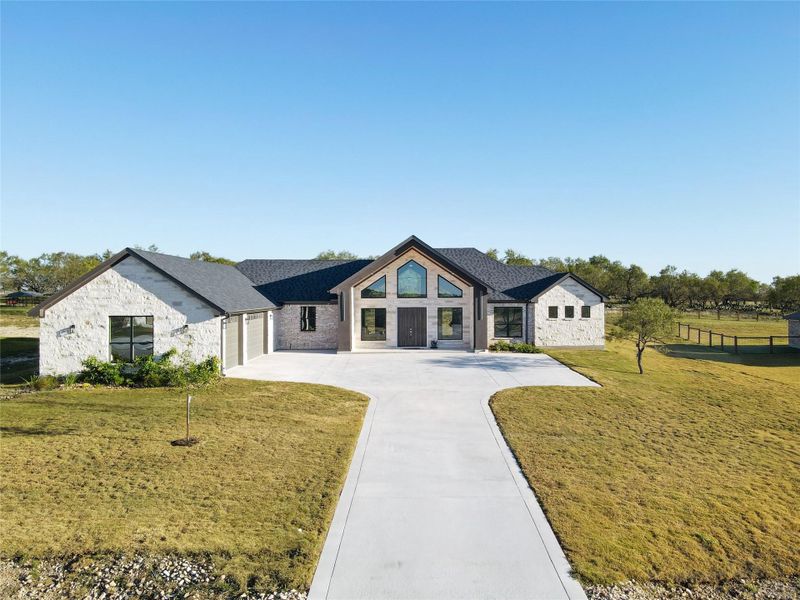 View of front of property with stone siding, a front lawn, and driveway