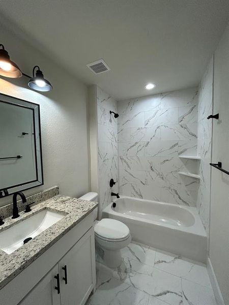 Full bathroom with tiled shower/bath combo, stylish vanity, mirror, light fixture