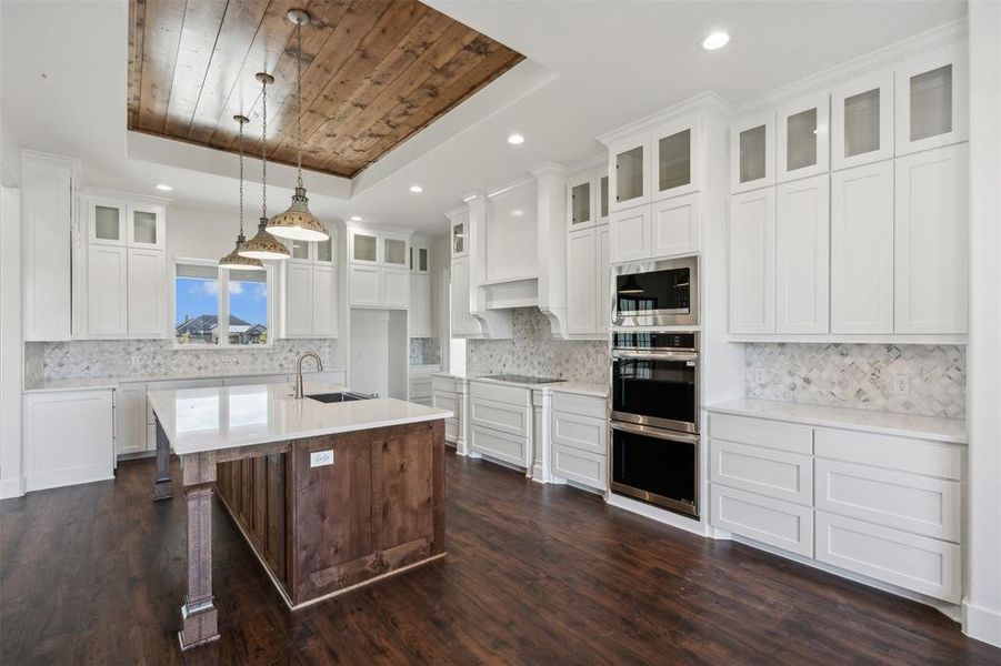 Kitchen featuring a tray ceiling, white cabinetry, sink, and dark wood-type flooring