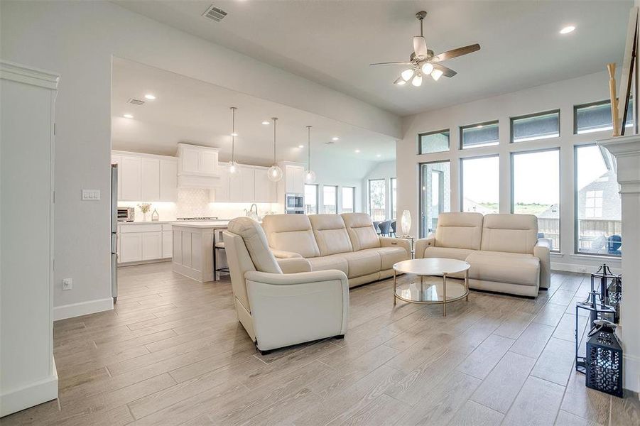 Living area featuring light wood finished floors, a ceiling fan, baseboards, and recessed lighting Living area featuring light wood finished floors, a ceiling fan, baseboards, and recessed lighting