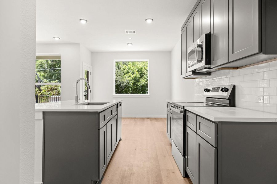 A contemporary kitchen showcasing light wood flooring and stainless steel appliances.