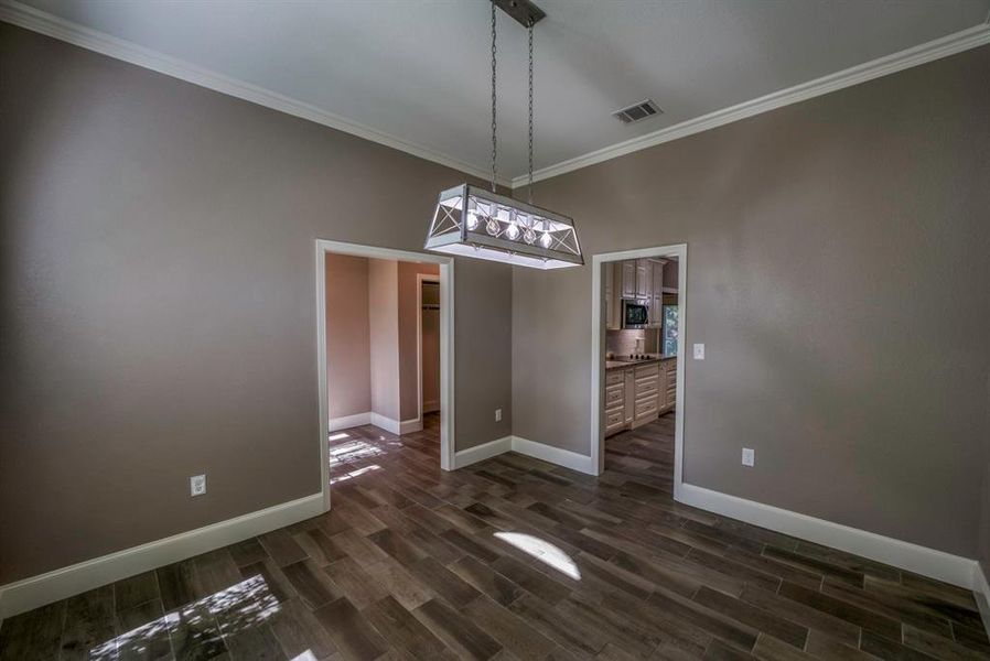 Dining area with dark wood tile flooring, a notable chandelier, and crown molding