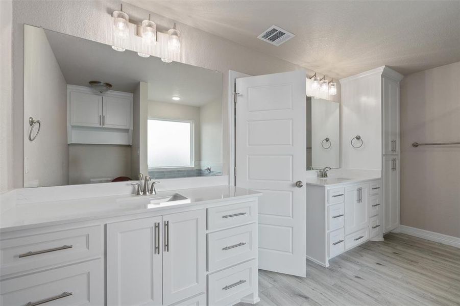 Bathroom featuring twin vanities with white cabinetry and integrated sinks Bathroom featuring twin vanities with white cabinetry and integrated sinks