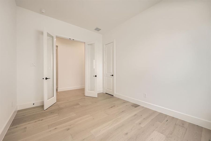 Spare room featuring light wood-type flooring, baseboards, and a smoke detector