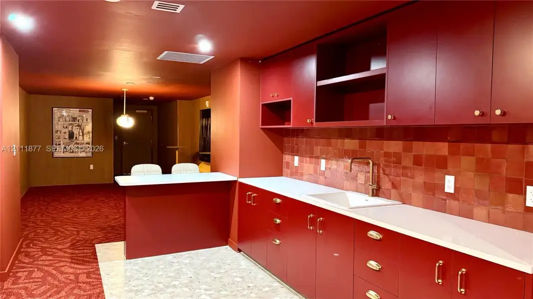 Custom kitchen cabinetry with brass-finish hardware, quartz countertops, a recessed sink with a gooseneck faucet, and a decorative tile backsplash