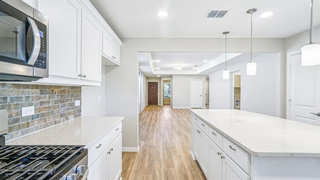 Kitchen featuring appliances with stainless steel finishes, white cabinets, tasteful backsplash, light wood-style floors, and recessed lighting Kitchen featuring appliances with stainless steel finishes, white cabinets, tasteful backsplash, light wood-style floors, and recessed lighting