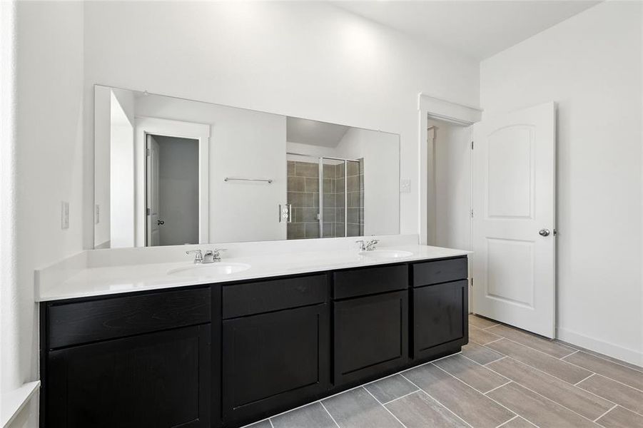 Full bathroom with double vanity, a shower stall, and wood finish floors Full bathroom with double vanity, a shower stall, and wood finish floors