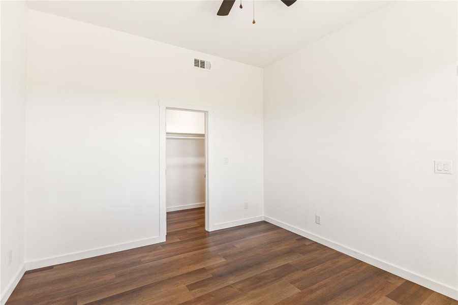 Room featuring wood-finish flooring, white walls, and a ceiling fan