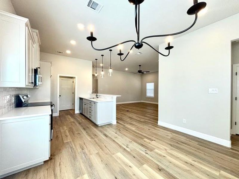 Kitchen featuring range, hanging light fixtures, ceiling fan, tasteful backsplash, and white cabinetry