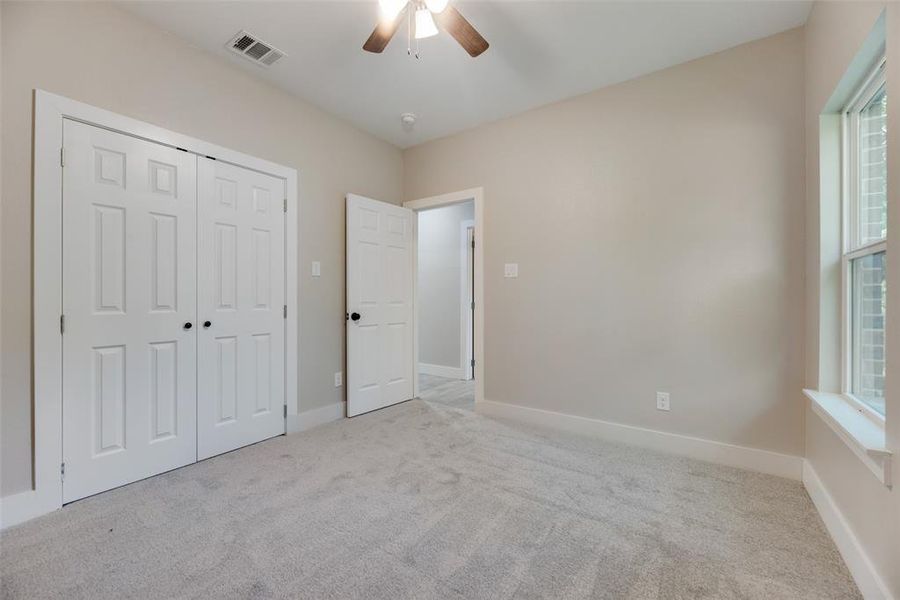 Unfurnished bedroom featuring multiple windows, light carpet, and ceiling fan