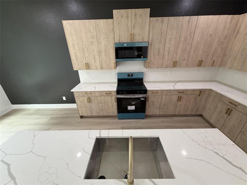 Kitchen featuring wood-finish cabinetry with gold-tone hardware, white countertops, built-in microwave, and a blue range Kitchen featuring wood-finish cabinetry with gold-tone hardware, white countertops, built-in microwave, and a blue range
