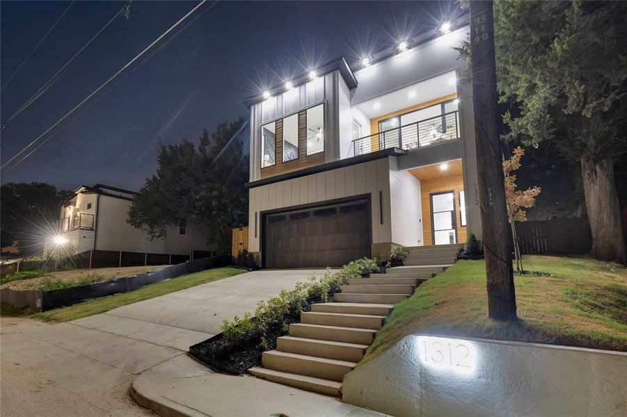 Contemporary house with a balcony, driveway, a garage, and stairway