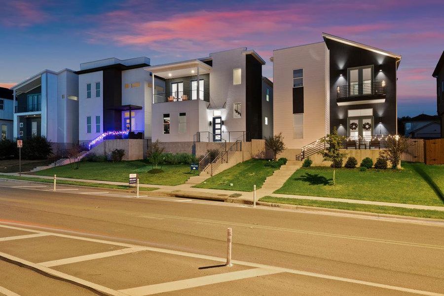 View of front of home with a balcony, a yard, and stucco siding