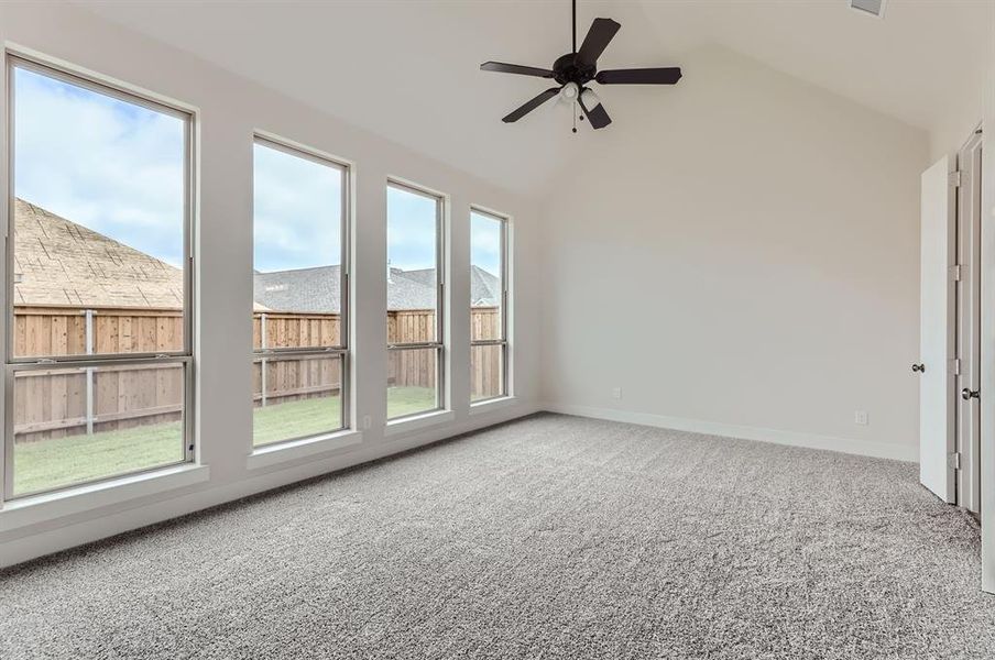 Carpeted empty room featuring ceiling fan and lofted ceiling