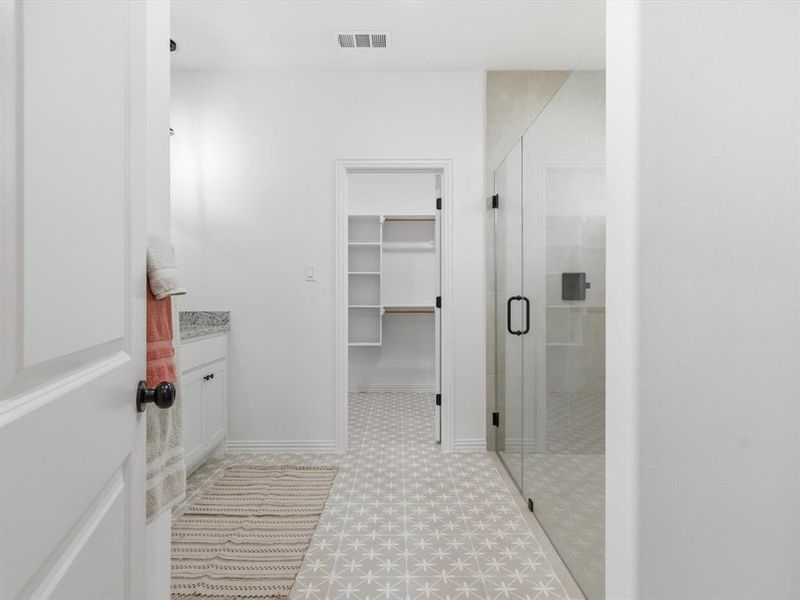 Spa-like primary bathroom has custom tile and inviting color scheme.