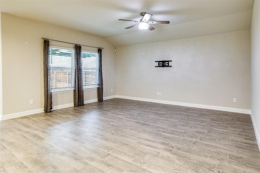 Unfurnished room featuring light wood-style flooring, vaulted ceiling, and a ceiling fan Unfurnished room featuring light wood-style flooring, vaulted ceiling, and a ceiling fan
