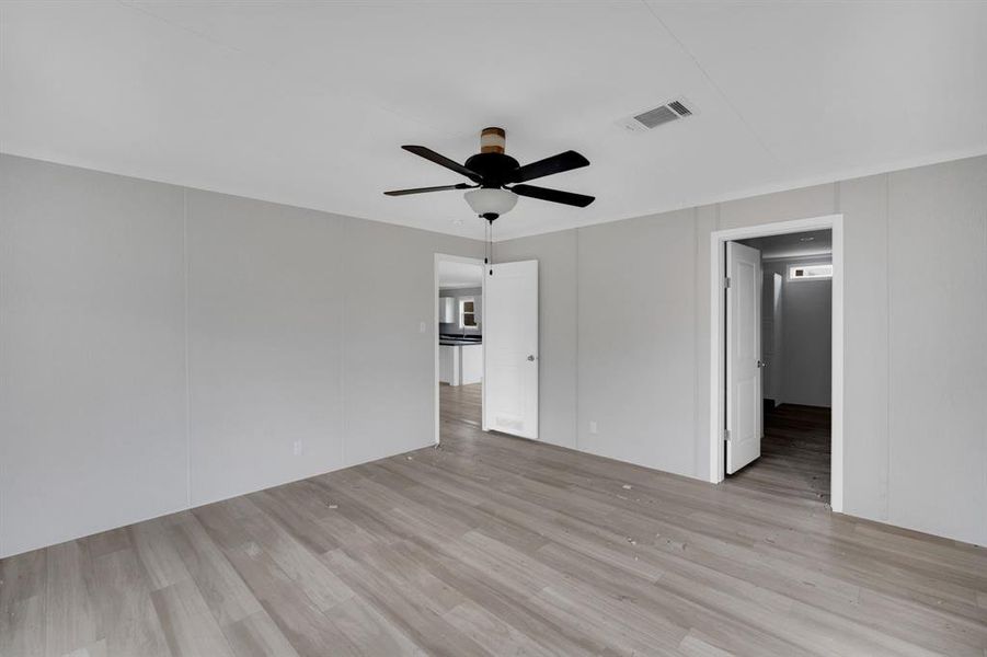 Empty room featuring light wood finished floors, ceiling fan, and a decorative wall