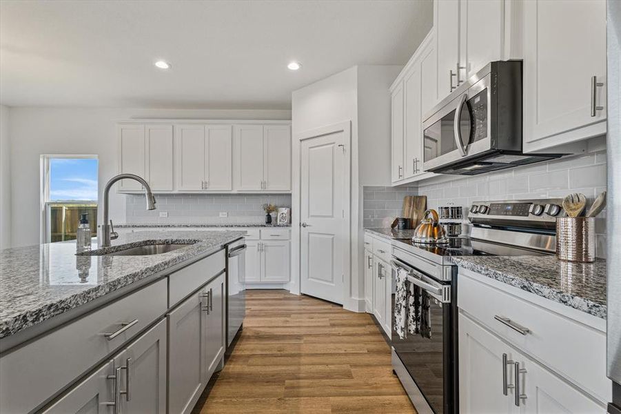 Kitchen featuring white cabinets, sink, light wood-type flooring, and stainless steel appliances Kitchen featuring white cabinets, sink, light wood-type flooring, and stainless steel appliances