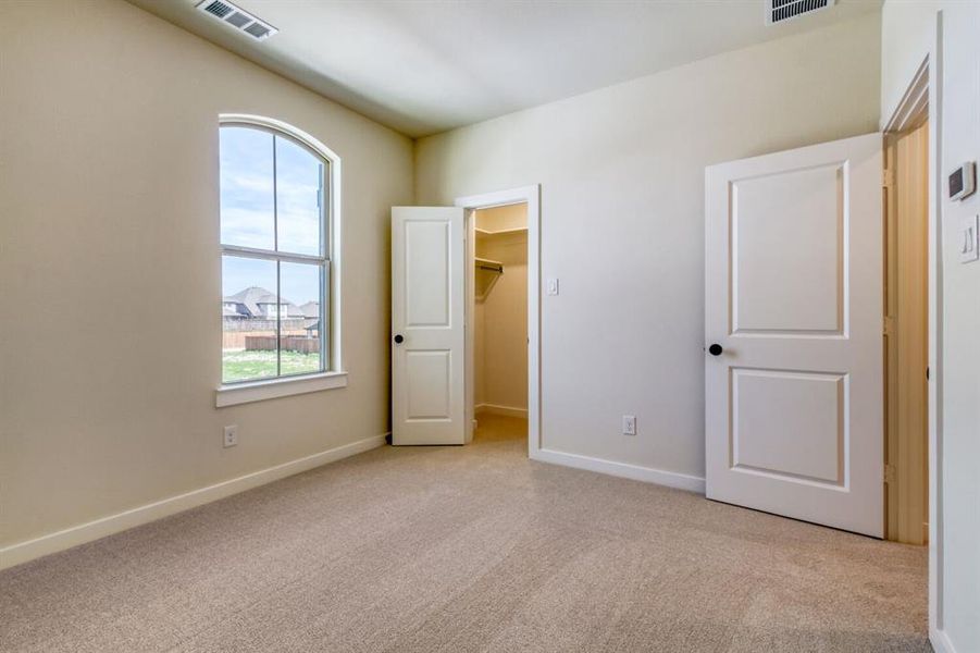 Unfurnished bedroom featuring a spacious closet and light carpet Unfurnished bedroom featuring a spacious closet and light carpet