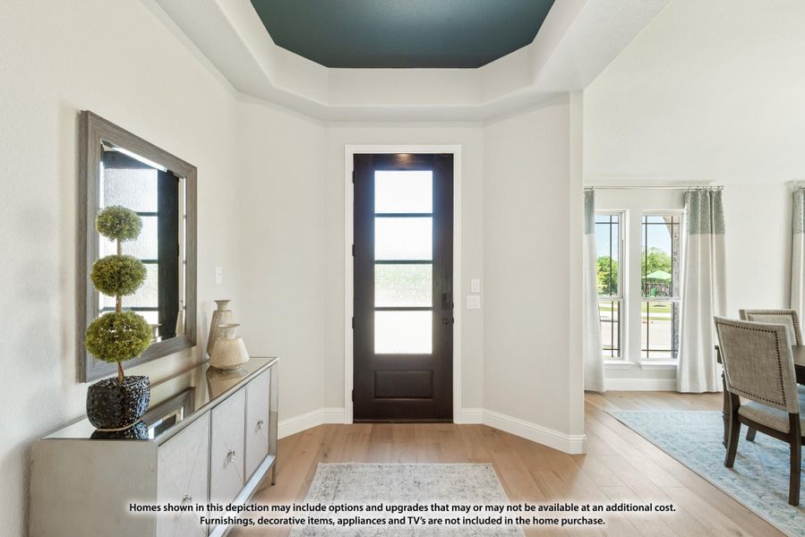 Foyer with dark front door, tray ceiling, hardwood floors, and console table with mirror Foyer with dark front door, tray ceiling, hardwood floors, and console table with mirror