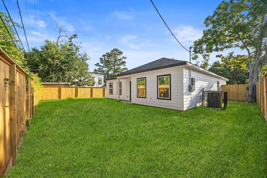 Spacious backyard with lush green lawn, surrounded by a wooden privacy fence, perfect for outdoor activities and gatherings.