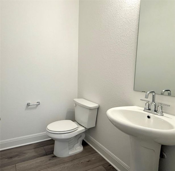 Half bathroom featuring wood finished floors and a textured wall Half bathroom featuring wood finished floors and a textured wall