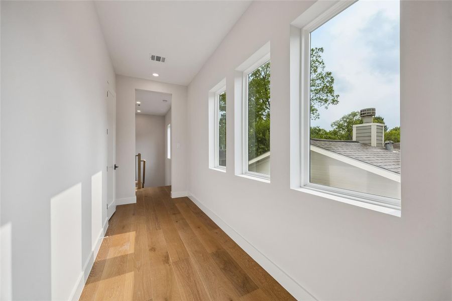 The entry into the primary suite creates separation from the rest of the second floor while oversized windows bring natural light into the space. Wide-plank flooring continue throughout the transition into the suite. The entry into the primary suite creates separation from the rest of the second floor while oversized windows bring natural light into the space. Wide-plank flooring continue throughout the transition into the suite.