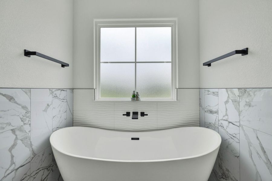 Freestanding soaking tub with a wall-mounted matte black faucet
