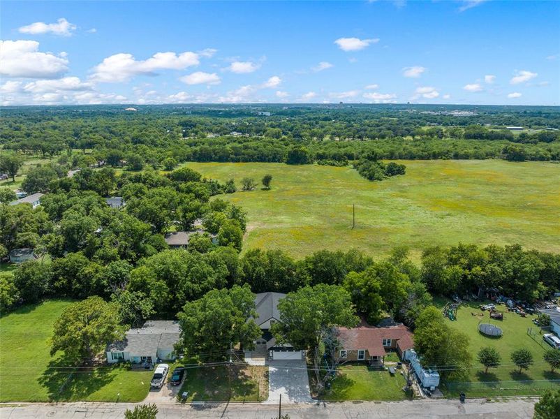 Aerial perspective showcasing a residential property with a dark roof and a paved driveway, surrounded by mature trees Aerial perspective showcasing a residential property with a dark roof and a paved driveway, surrounded by mature trees