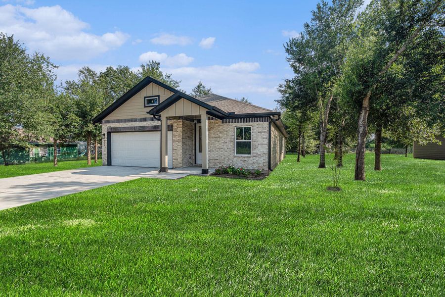 Charming brick home with a contemporary design, featuring a gabled roof and front porch. It includes a spacious two-car garage and sits on a lush, well-maintained lawn with mature trees, offering a serene and inviting setting.