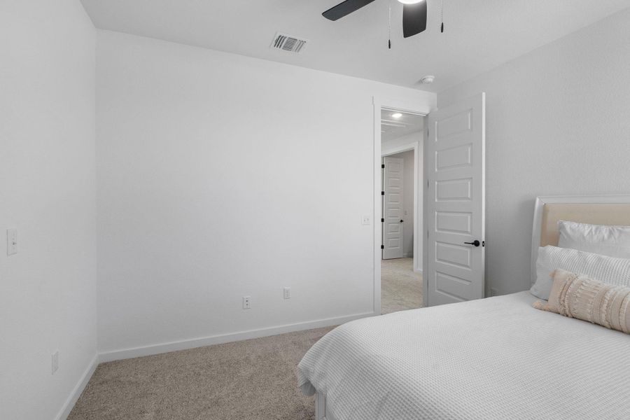 Bedroom 3 featuring visible vents, baseboards, light colored carpet, and ceiling fan