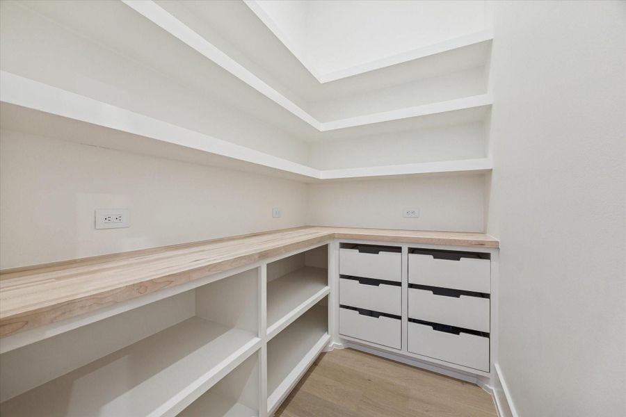 Thoughtfully designed walk-in pantry featuring custom built-ins and electrical outlets for seamless organization and functionality.
